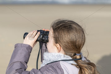 Girl observing with binoculars in winter  France