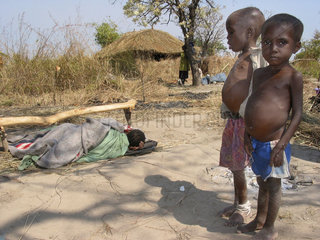 Malnourished boys at an MSF feeding centre stand in front of a severely ill boy lying in a blanket. Feeding centres and other humanitarian aid were organised in Angola after widescale malnutrition during and following the countrys civil war.