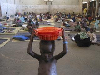 A malnourished child carrying food bowls at a feeding centre in Angola. Feeding centres and other humanitarian aid were organised in Angola after widescale malnutrition during and following the countrys civil war.