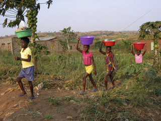 A group of girls carry food  water and other supplies on their heads. Feeding centres and other humanitarian aid were organised in Angola after widescale malnutrition during and following the countrys civil war.