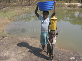Children carry containers of water from a local pond. Feeding centres and other humanitarian aid were organised in Angola after widescale malnutrition during and following the countrys civil war.