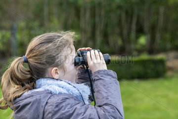 Girl observing with binoculars in winter  France