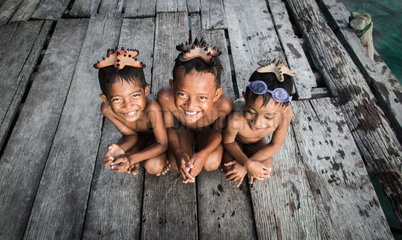 Three boys with a sea star on their head. These children are part of the Banaux or nomadic seas. They live on the Togians archipelago in Indonesia