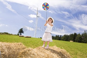 Little girl playing with a reel on a haystack France