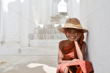 Teenager disguised as a monk playing on the steps of a pagoda in Burma in the city of Mandalay