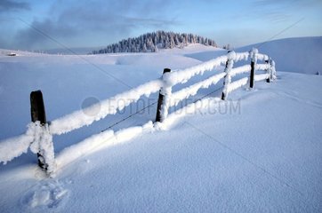 Zaun mit Schnee in Semnoz im Winter wälzt Frankreich