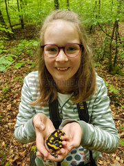 Young girl discovers a spotted salamander in Queen's Forest  Lorraine  France