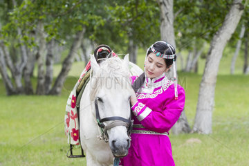 Mongol woman traditionnaly dressed with a horse  Mode  Bashang Grassland  Zhangjiakou  Hebei Province  Inner Mongolia  China
