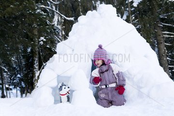 Girl playing with a teddy bear of Huskies near the igloo