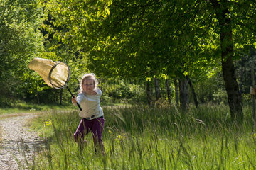 Girl having fun pursuing and catching some butterflies to observe them in a meadow  Alpes de Haute Provence  France
