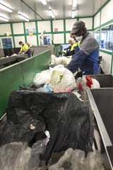 Employees of a waste facility on a conveyor belt sorting line. Manual sorting of plastic to to separate non-recyclable plastic PET (polyethylene terephthalate) objects. Some qualities of plastics can not be recycled and should be incinerated. PETs used in water bottles and juices instead can be recycled  for example  into garment fabrics. Portugal