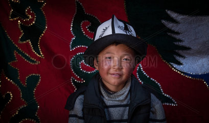 Young Kyrgyz with a kalpak  traditional hat. Image taken in a yurt in the mountains of Kyrgyzstan