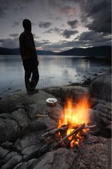 Man bivouacing at the edge of water at twilight Norway