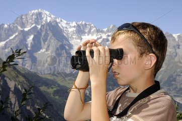 Boy looking through binoculars in the Alps France