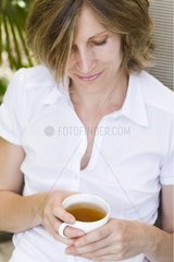 Woman sitting and holding a cup of tea in his hands