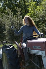Young red-haired girl on a tractor in a garden