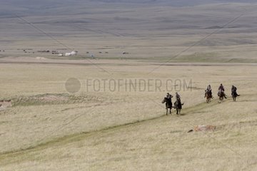 Horsemen trotting in pastures near lake Son Kul Kyrgyzstan