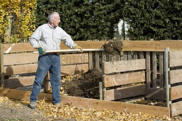 Man turning around the compost in a garden in autumn