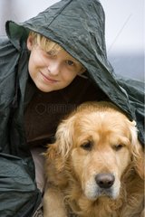 Junge mit Hund unter einem Regenpfad wÃ¤hrend eines Regengusses