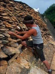 Man posing stones to build its roof France