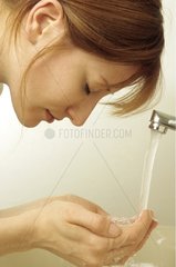 Junge Frau wäscht ihr Gesicht mit Wasser
