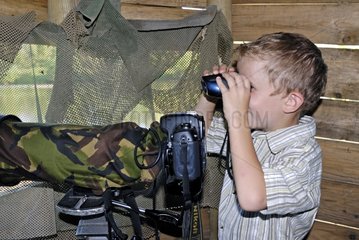 A boy looking through binoculars in a lookout France