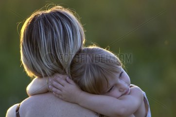 Kleines Mädchen in den Armen ihrer Mutter