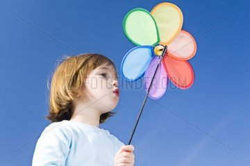 Little girl with a windmill on a blue sky