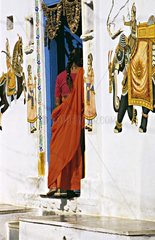 Woman entering in a house decorated with paintings India