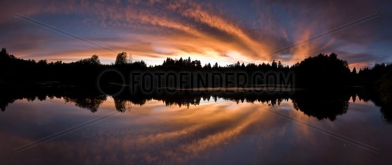 High clouds reflections at sunset in pond Bressone