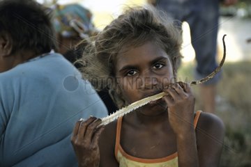 Aborginal girl eating a sand monitor in Australia