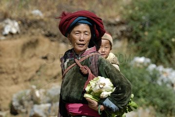 Mosofrau mit einem Kind im Rücken Yunnan China trägt