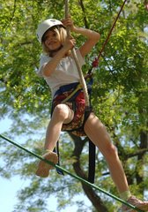Young girl on a rope bridge in tree climbing