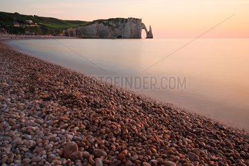 Limestone cliffs of Etretat and pebble beach at sunset