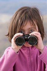 Little Girl watching with binoculars in dry hills