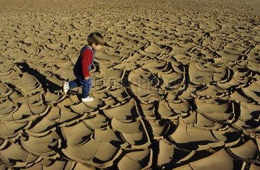 Little boy walking on a dry and cracked earth in France