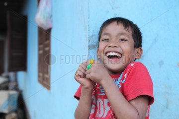 Portrait of a child laughing while eating a candy in Laos