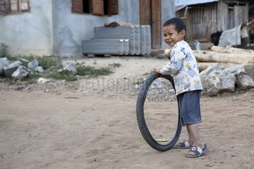 Boy playing was pushing a wheel in Laos
