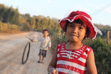Portrait of a girl and boy pushing a wheel in Laos