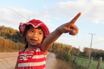 Girl pointing at the sun setting in Laos