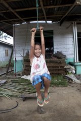 Girl playing with a swing outside his home Sumatra