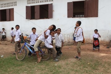 Two children on a bicycle in front of a classroom in Laos