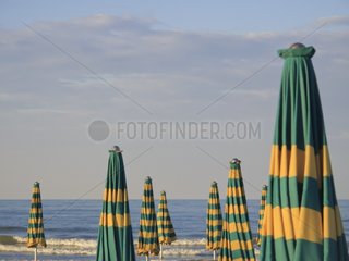 Rows of sun umbrellas and long chairs Adriatic coast Italy