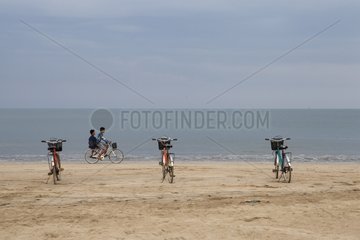 Children biking on the beach at Chaung Tha Burma