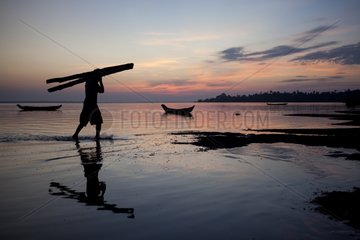 Man emptying his boat filled timber in Burma