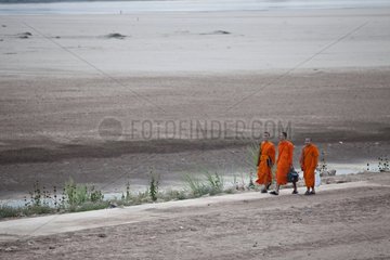 Monks walking along the Mekong in dry season Laos