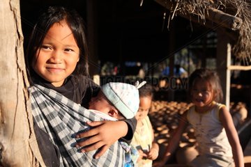 Girl carrying her sister against her in Laos