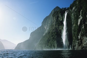 Waterfall and a view of Milford Sound fjord Tasman Sea