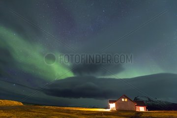 House illuminated under an Aurora Borealis South Iceland