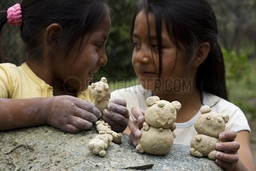 Girls playing with Spectacled Bear figurines Ecuador